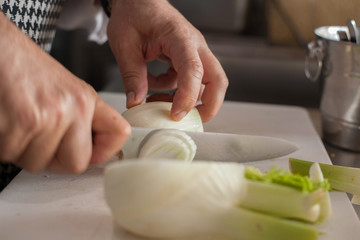Obraz na płótnie Canvas Chef cutting onions on white board