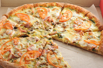 pizza cut into slices with mushrooms, tomatoes, cheese and bacon