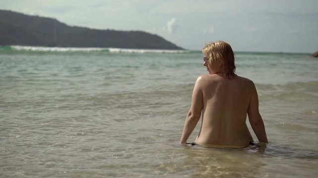 Young sexy woman sunbathing in sea or ocean
