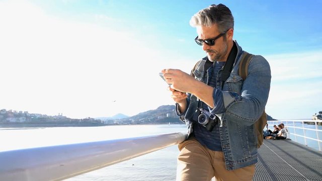 Man taking picture with smartphone, beach scenery