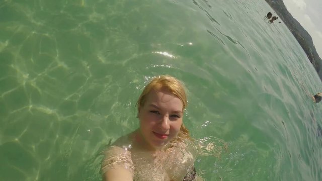 Blonde woman taking selfie video on a beach
