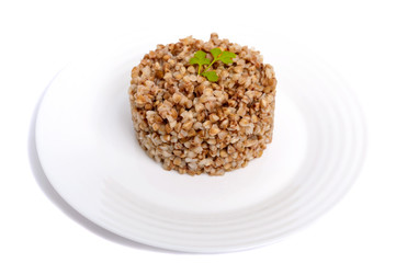 Buckwheat porridge in the form of a circle on a white plate on a white background. Dietary, vegan, Lenten dish. Isolate object.