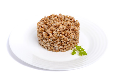 Buckwheat porridge in the form of a circle on a white plate on a white background. Dietary, vegan, Lenten dish. Isolate object.