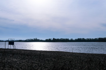 Evening landscape. View of the winter river. Deserted beach with an observation unit.
