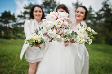 Pretty bride with bridesmaids on white dresses with bouquets on