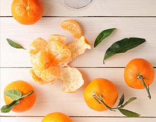 tangerines with green leaves on wooden background
