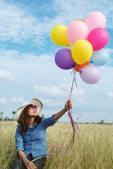 Beautiful woman at meadow with balloons in hand.