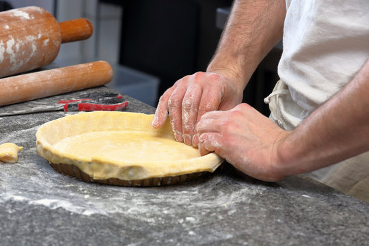 Baker kneading dough for tart in a bakery