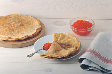 red caviar in the spoon and pancakes in plate
