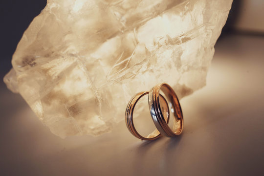 beautiful gold wedding rings lying near crystal stone