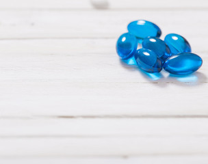 blue  pills  on white wooden background