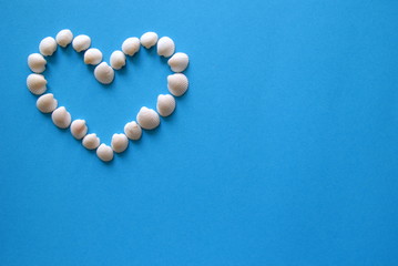 A heart from different seashells on the blue background for Valentine's Day.