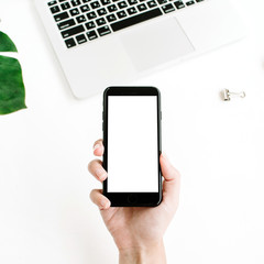 Mockup of smartphone with blank screen in female hand. Flat lay, top view workspace