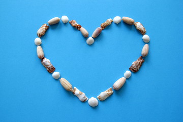 A heart from different seashells on the blue background for Valentine's Day.
