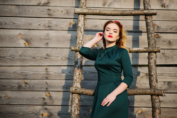 Yong elegance blonde girl at green dress background wooden stair