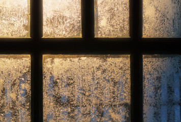frosty pattern on the window glass lit by sunlight