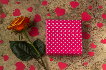 Gift box, rose flower and hearts on a wooden background