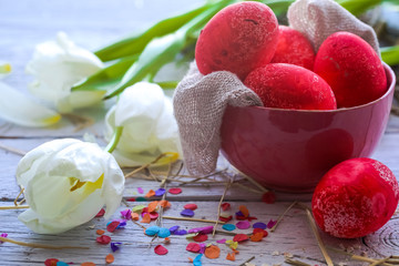 Easter still life with colored eggs in a plate and white tulips