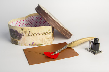 Valentine concept: Writing quill and a love letter, heart shaped LOVE inscribed symbol, white background