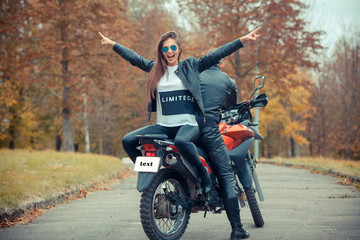 Fototapeta premium Pretty girl with a biker posing near a sports bike. Beautiful couple with a motorcycle at sunset