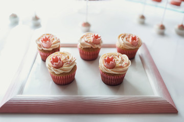 Pretty cupcakes with cream and little pink crowns on them stand