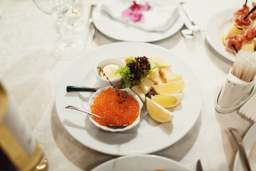 Red caviar and slices of lemon on white tray