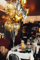 Golden and silver balloons in form of stars hang over dinner tab