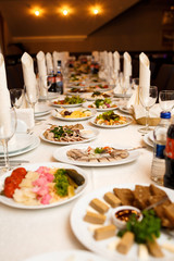 Rolls of white serviettes stand on dinner plates on long table