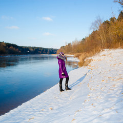 teen girl walking in the winter on the bank of a frozen river. Girl teenager goes away