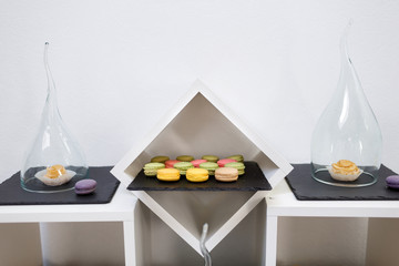 Macaroons on black plate in white cube on candy buffet