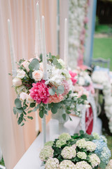 White candleholder with white roses and pink peonies stands befo
