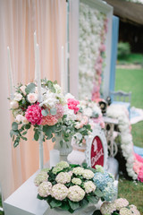 White candleholder with white roses and pink peonies stands befo