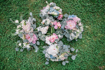 Obraz na płótnie Canvas Wedding bouquets of pink and blue flowers lie on green lawn