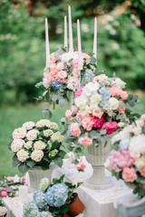 White, pink and blue hydrangeas in Greek vases stand outside