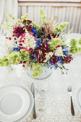 Stunning bouquet of red, white and blue flowers stands on white