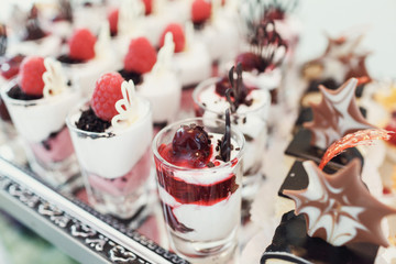 Shots with cold desserts of cream and cherries stand on glass tr