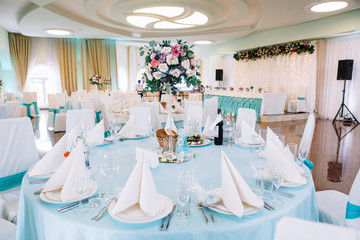 White plates with beige serviettes on them stand on blue dinner