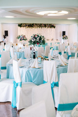 White chairs decorated with blue ribbons stand around dinner tab
