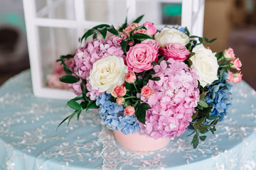Pretty pink bouquet of hydrangeas and roses stands on blue dinne