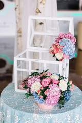 Pretty pink bouquet of hydrangeas and roses stands on blue dinne