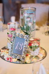 Frame with number 13 stands on mirror tray with flowers