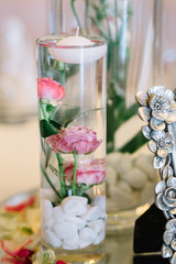 Pink roses put in glass vase with water and little candle