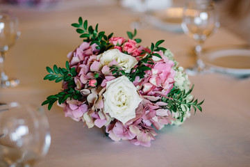 Little bouquet of pink hydrangeas and white roses stands on beig