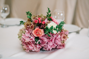 Little bouquet of pink hydrangeas and orange roses stands on bei