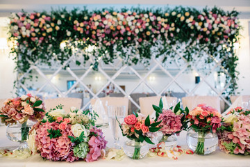 Look from behind the row of bouquets at mirror wall with garland