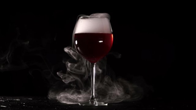 Isolated glass with wine smoke on black background. Red alcohol with white fume in Beautiful elegant glassing cup with long thin leg for alcoholic beverages presented in interesting format. Smoking