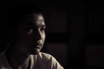 Obraz premium Sad young man thinking in dork room,Low key style.