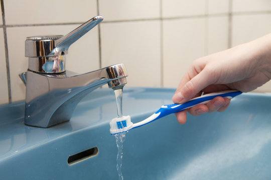 Zahnb&uuml;rste mit Zahncreme unter einem Wasserhahn