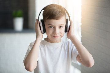 Happy smiling child enjoys listens to music in headphones over orange background