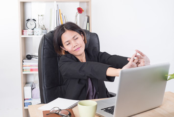 asian businesswoman sitting at the table computer in office with stretching arms.